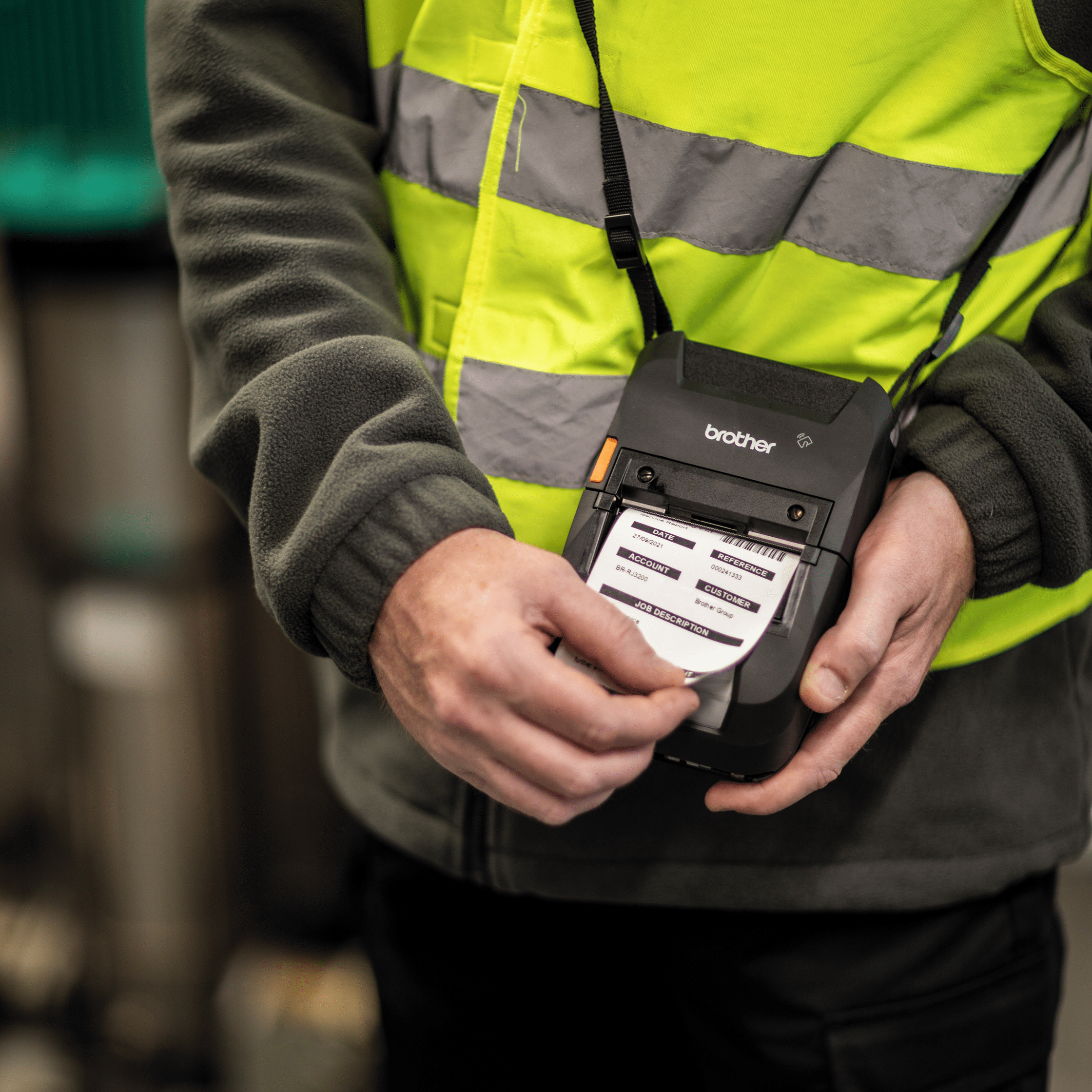 portable printer brother rj-3250wb with print out being used with shoulder strap by a person in high vis